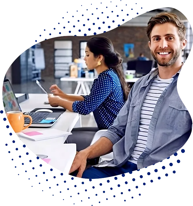 Hombre sonriente mirando a cámara y mujer concentrada trabajando en una Agencia de Marketing Digital, él con chaqueta gris y ella con blusa azul de puntos, en un ambiente de oficina moderno.